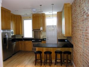 Functional small kitchen that blends the granite, brick and cherry cabinets to soften the stainless accents