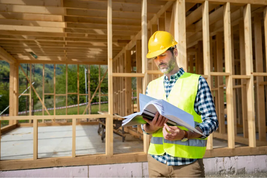 Engineer with hard hat and blueprints at a build site